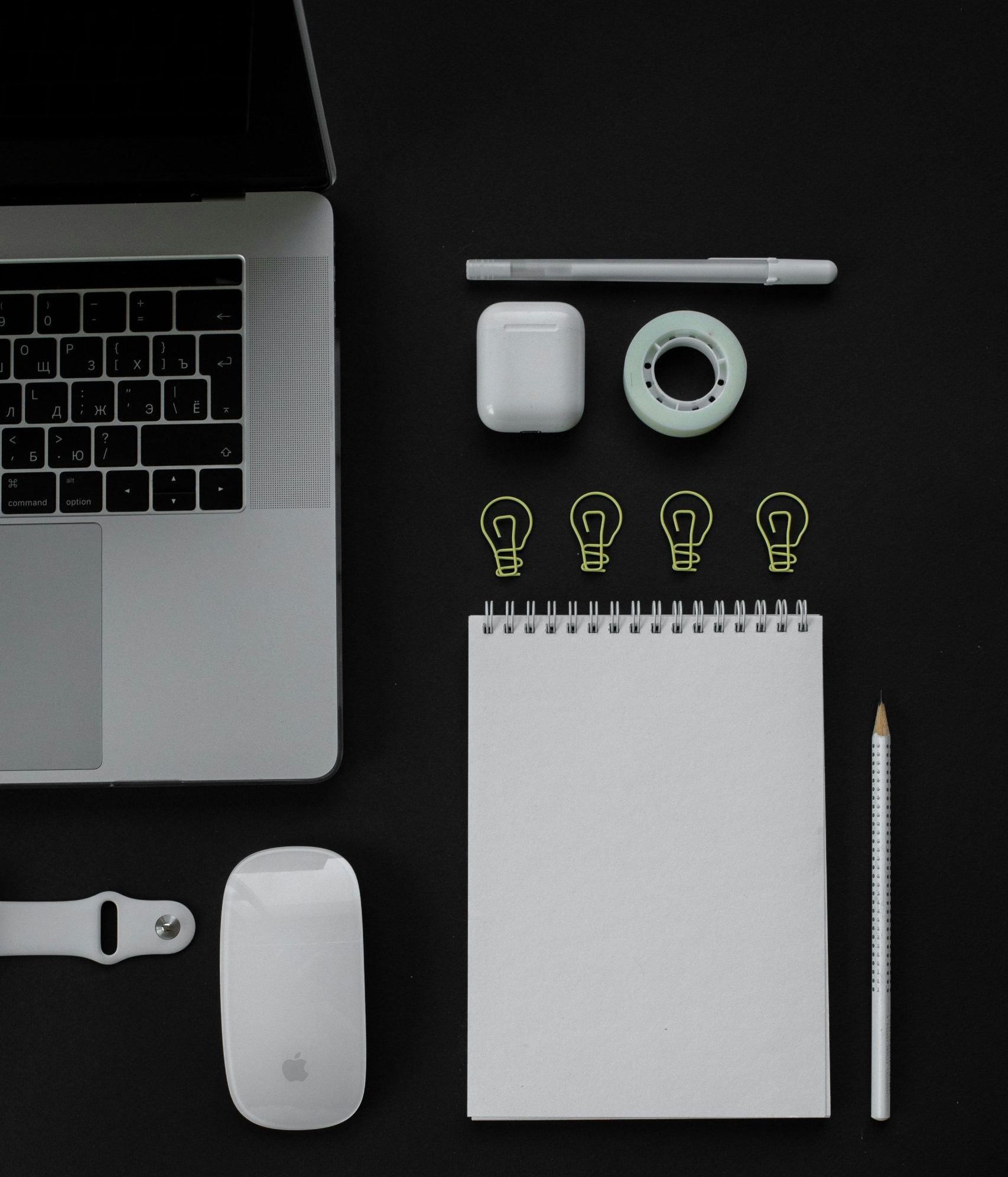 vue de dessus de lapartie droite d'un mac avec souris bloc note boitier airpod apple pen un carnet de note et 4 petites ampoules dessinées au dessus