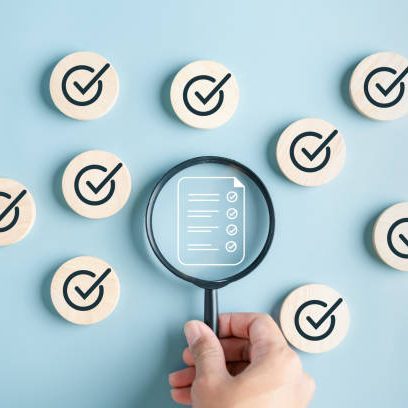 Loupe vérifiant une checklist au milieu de pastilles blanches avec le signe validé.